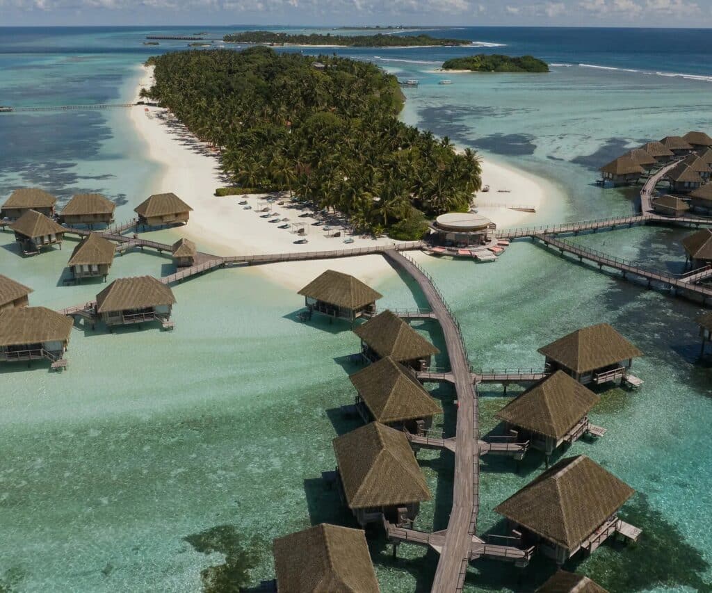 Vue aérienne d’un resort tropical avec villas sur pilotis et plage