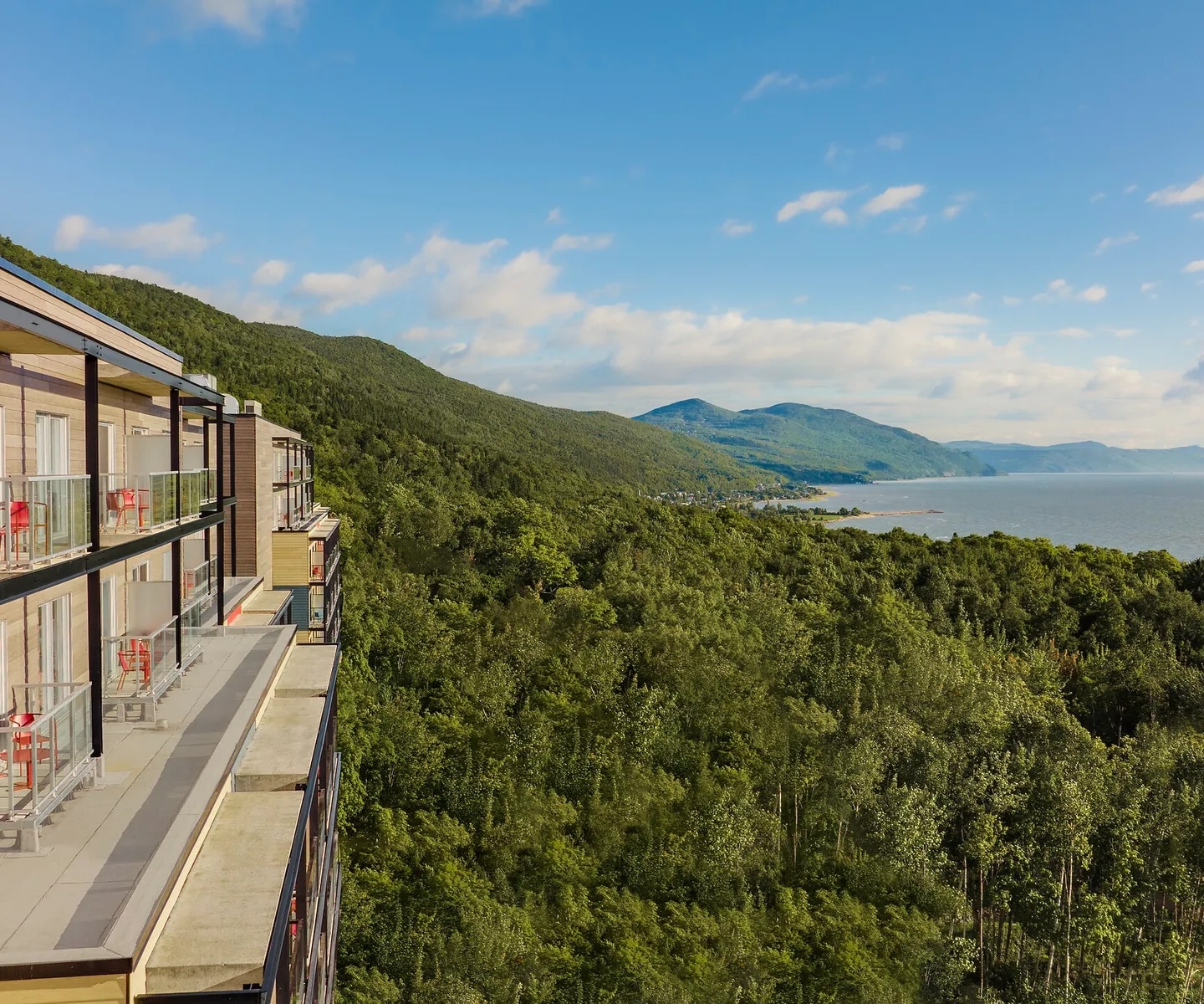 http://Bâtiment%20d’hôtel%20avec%20balcons%20surplombant%20une%20forêt%20et%20une%20baie