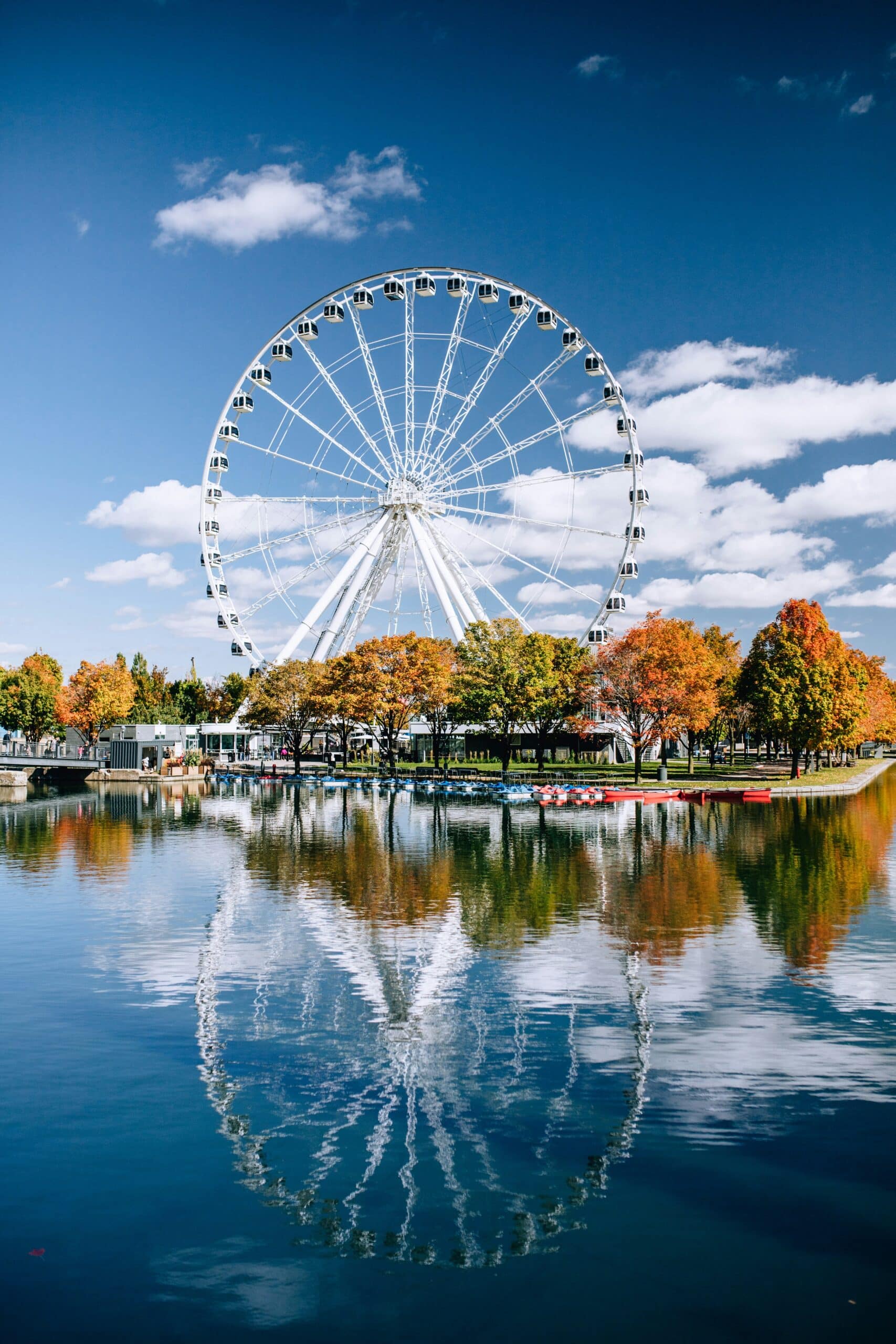 http://Grande%20Roue%20de%20Montréal%20se%20reflétant%20dans%20le%20bassin%20du%20Vieux-Port%20sous%20un%20ciel%20bleu.