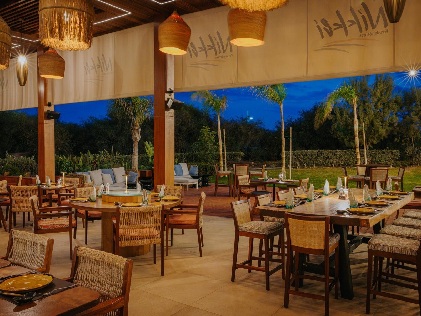 http://Restaurant%20d’hôtel%20en%20terrasse%20le%20soir%20avec%20tables%20dressées%20et%20éclairage%20chaleureux
