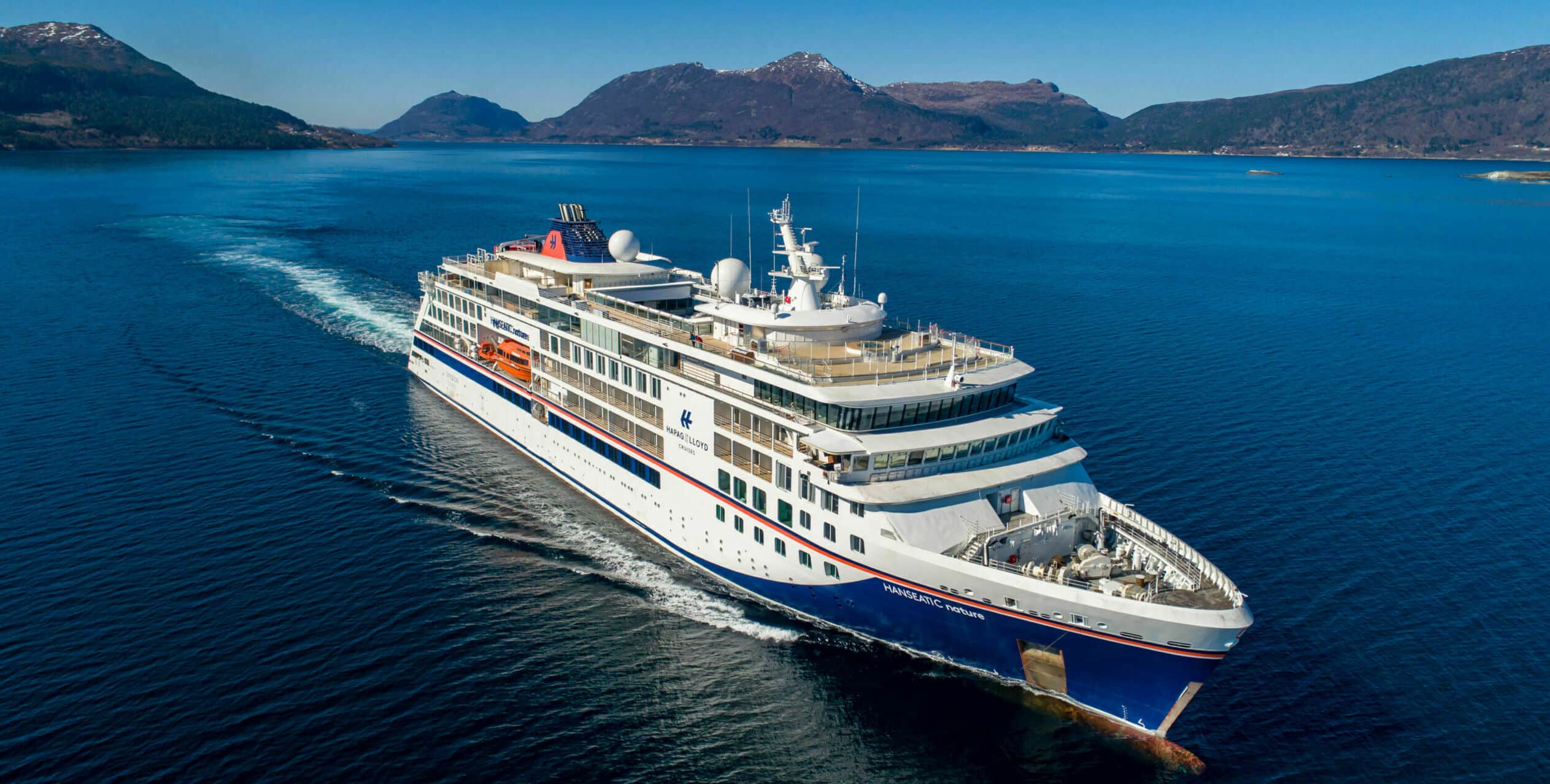 http://Bateau%20de%20croisière%20en%20mer%20entouré%20de%20montagnes%20sous%20ciel%20dégagé