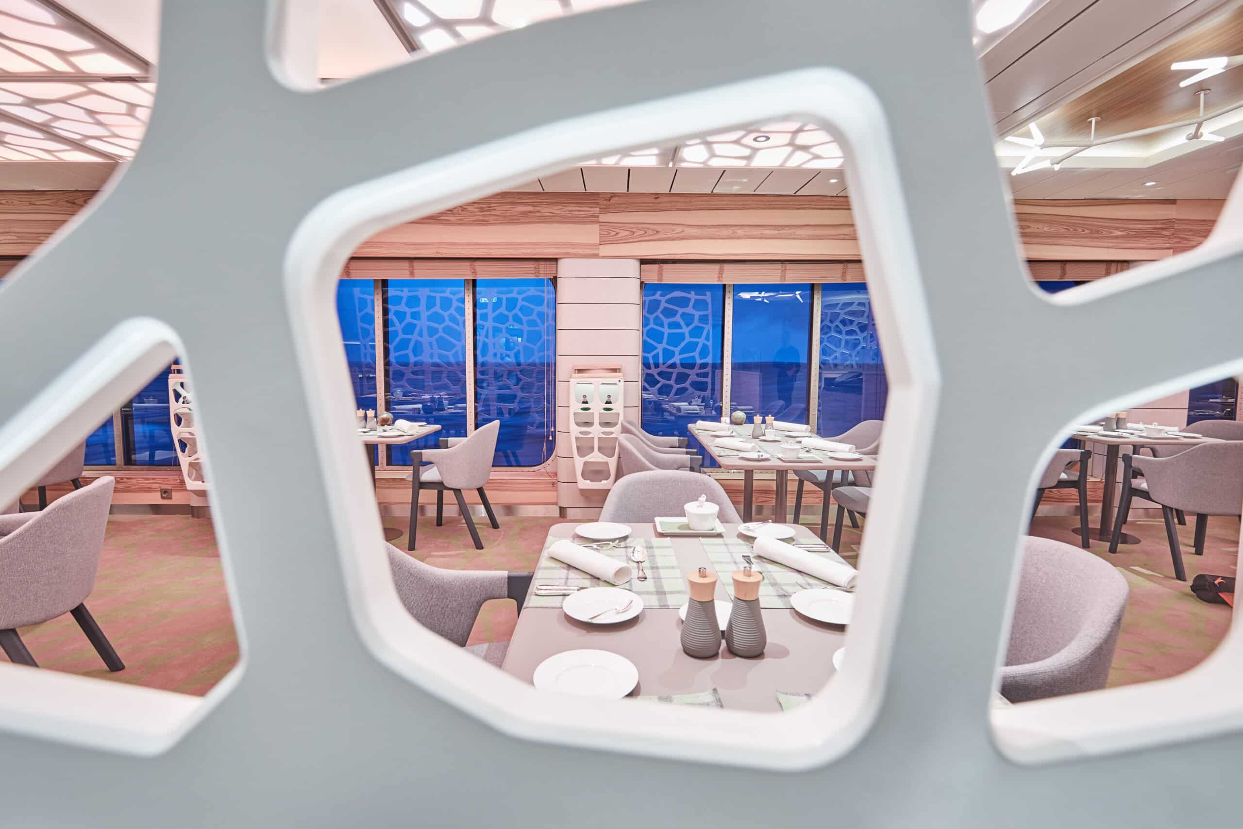 http://Restaurant%20élégant%20vu%20à%20travers%20une%20structure%20décorative%20avec%20tables%20dressées%20et%20vue%20sur%20la%20mer