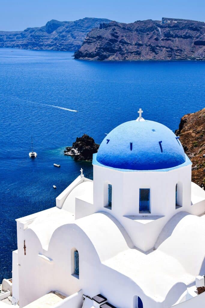 Église blanche au dôme bleu dominant la mer Égée à Santorin en Grèce