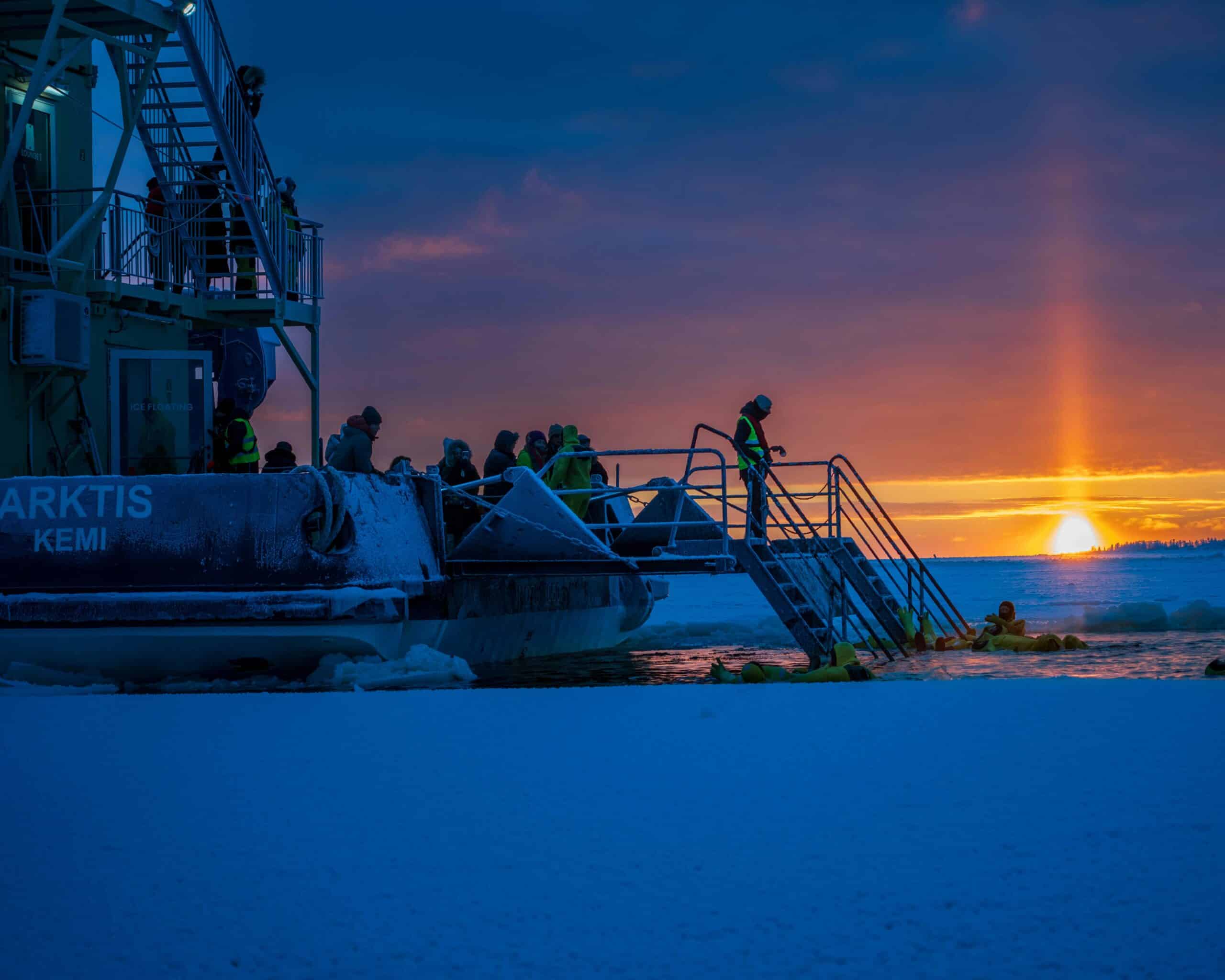 http://Voyageurs%20participant%20à%20une%20baignade%20dans%20les%20glaces%20au%20coucher%20du%20soleil%20en%20Laponie%20finlandaise