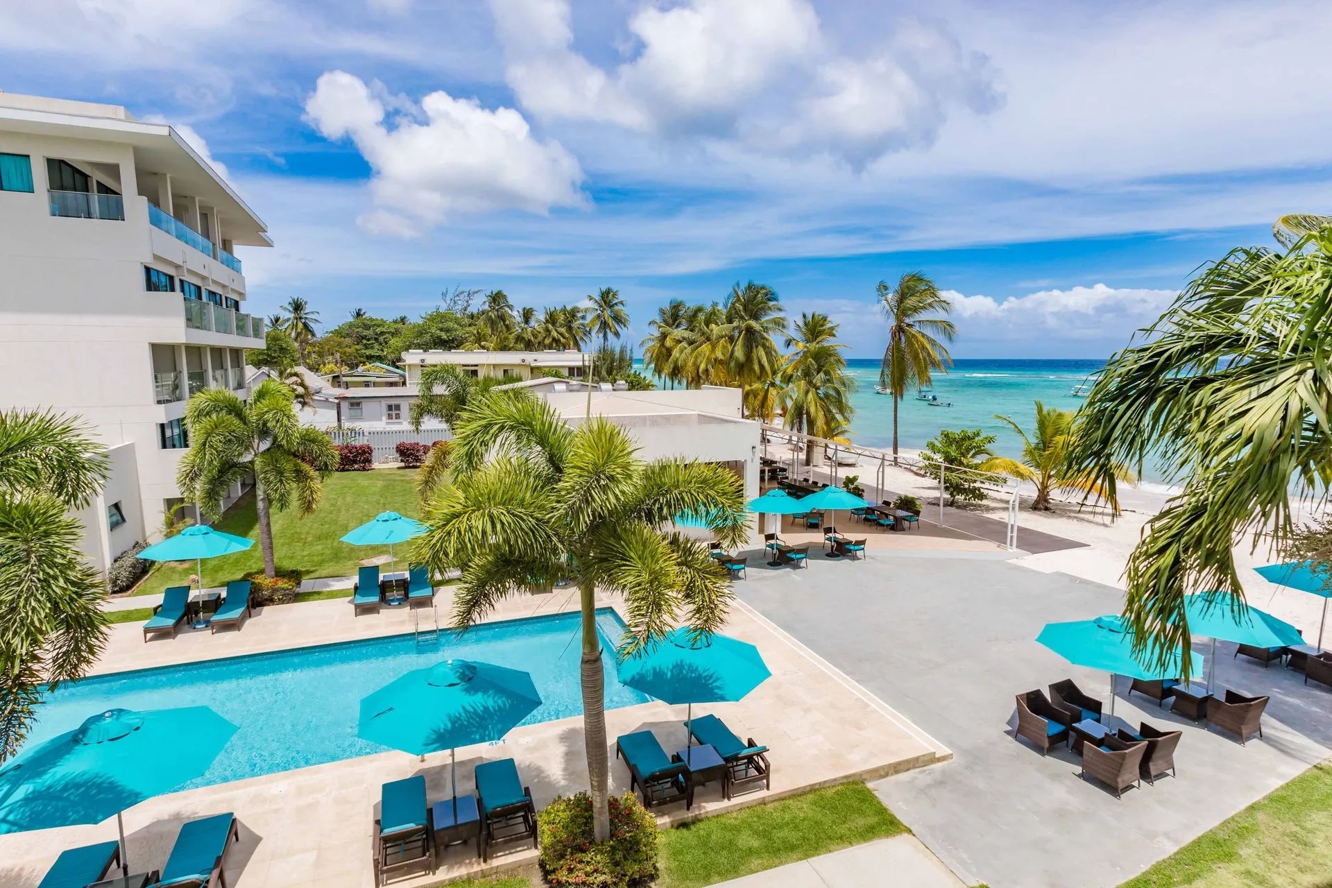 http://Complexe%20hôtelier%20en%20bord%20de%20mer%20avec%20piscine%20extérieure,%20palmiers%20et%20accès%20direct%20à%20une%20plage%20de%20sable%20blanc.