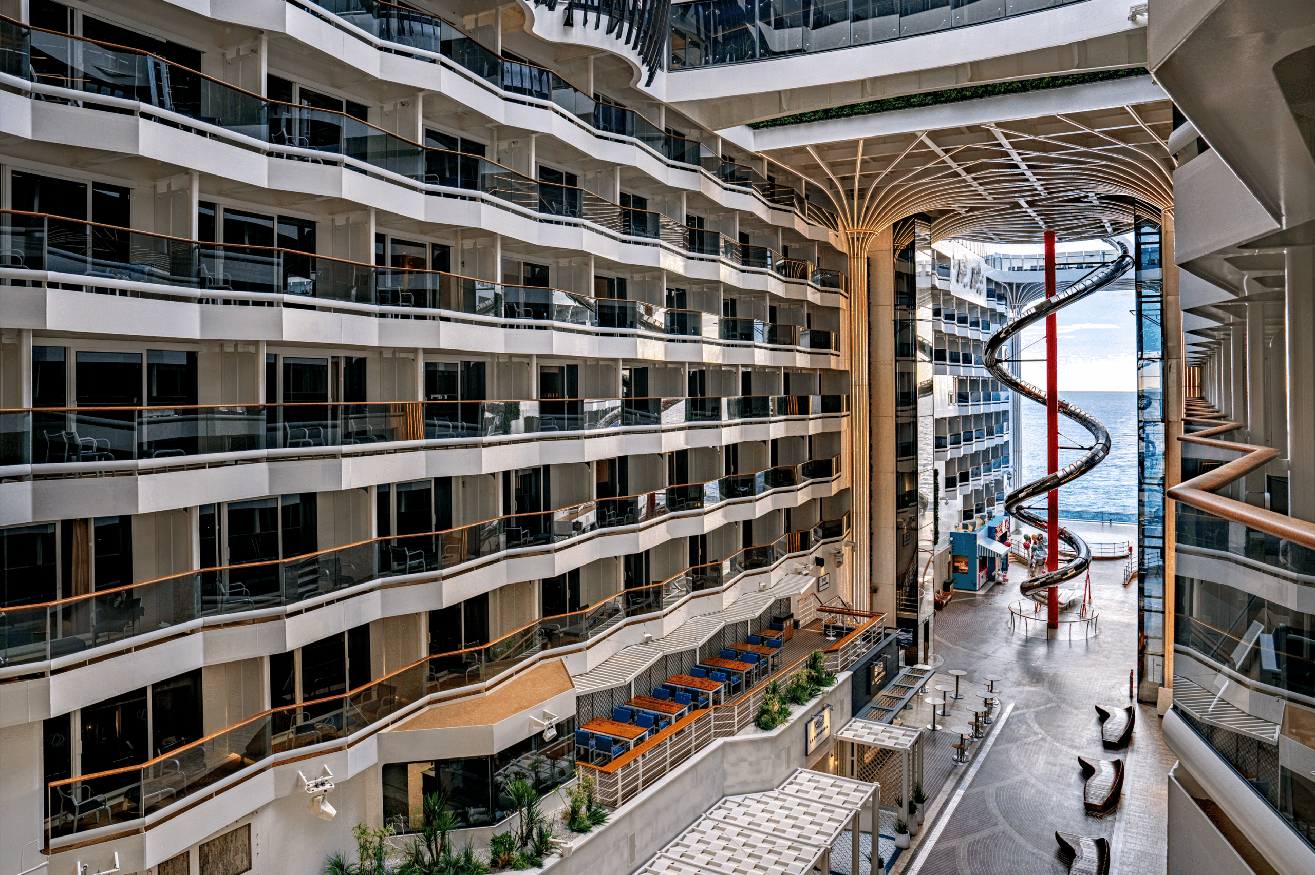 http://Atrium%20moderne%20d’un%20navire%20de%20croisière%20avec%20balcons,%20espaces%20communs%20et%20grand%20toboggan%20intérieur.