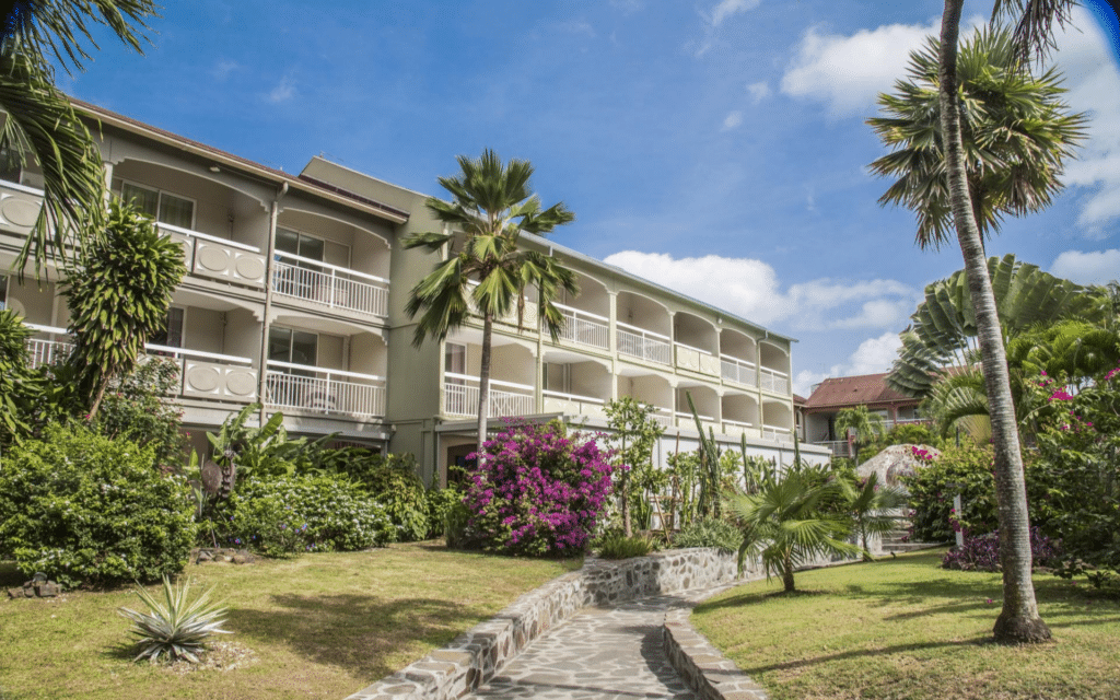Bâtiment d'hébergement entouré de jardins tropicaux et de palmiers dans une résidence en Martinique.