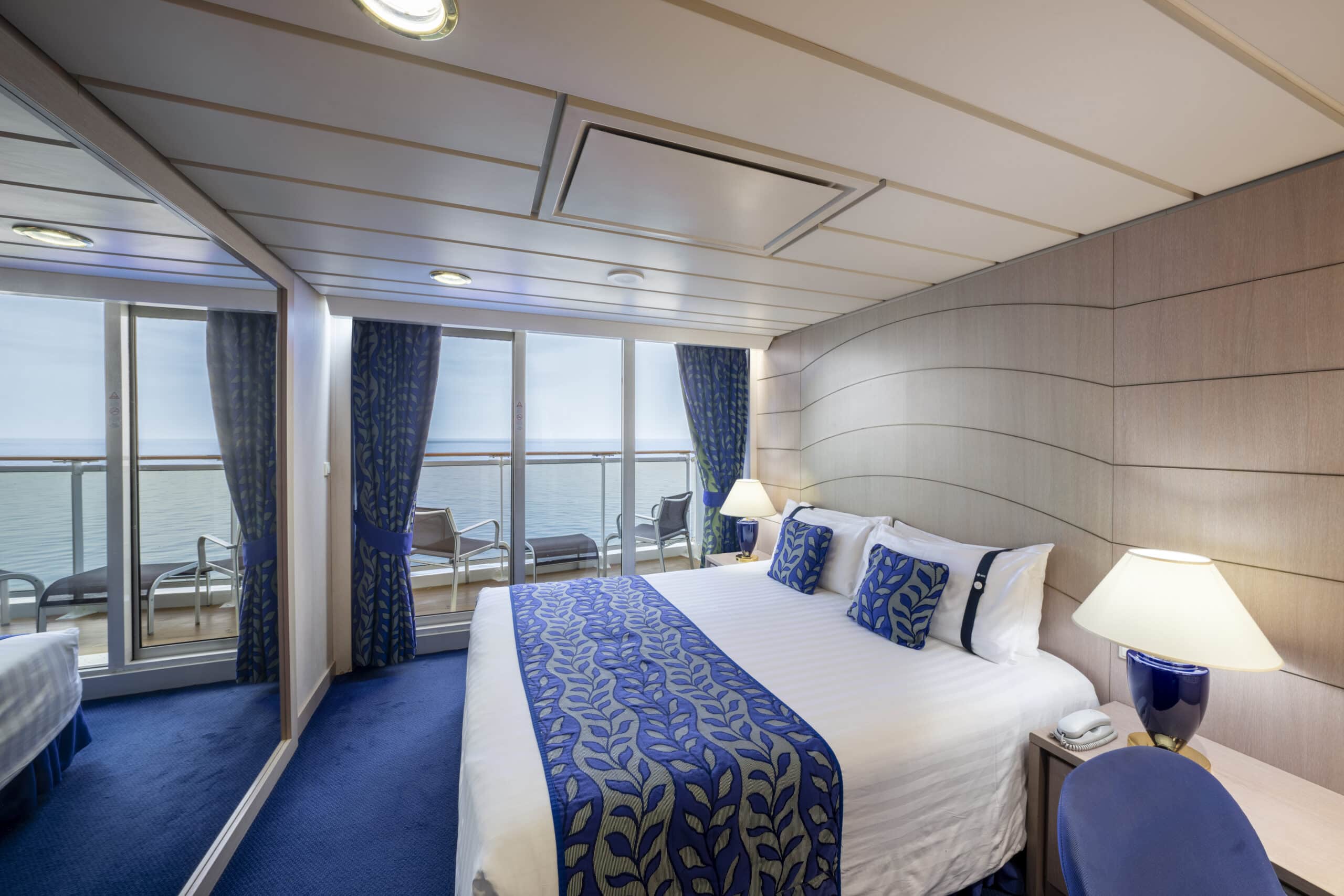 http://Cabine%20de%20croisière%20élégante%20avec%20grand%20lit%20double,%20balcon%20privé%20et%20vue%20sur%20la%20mer.