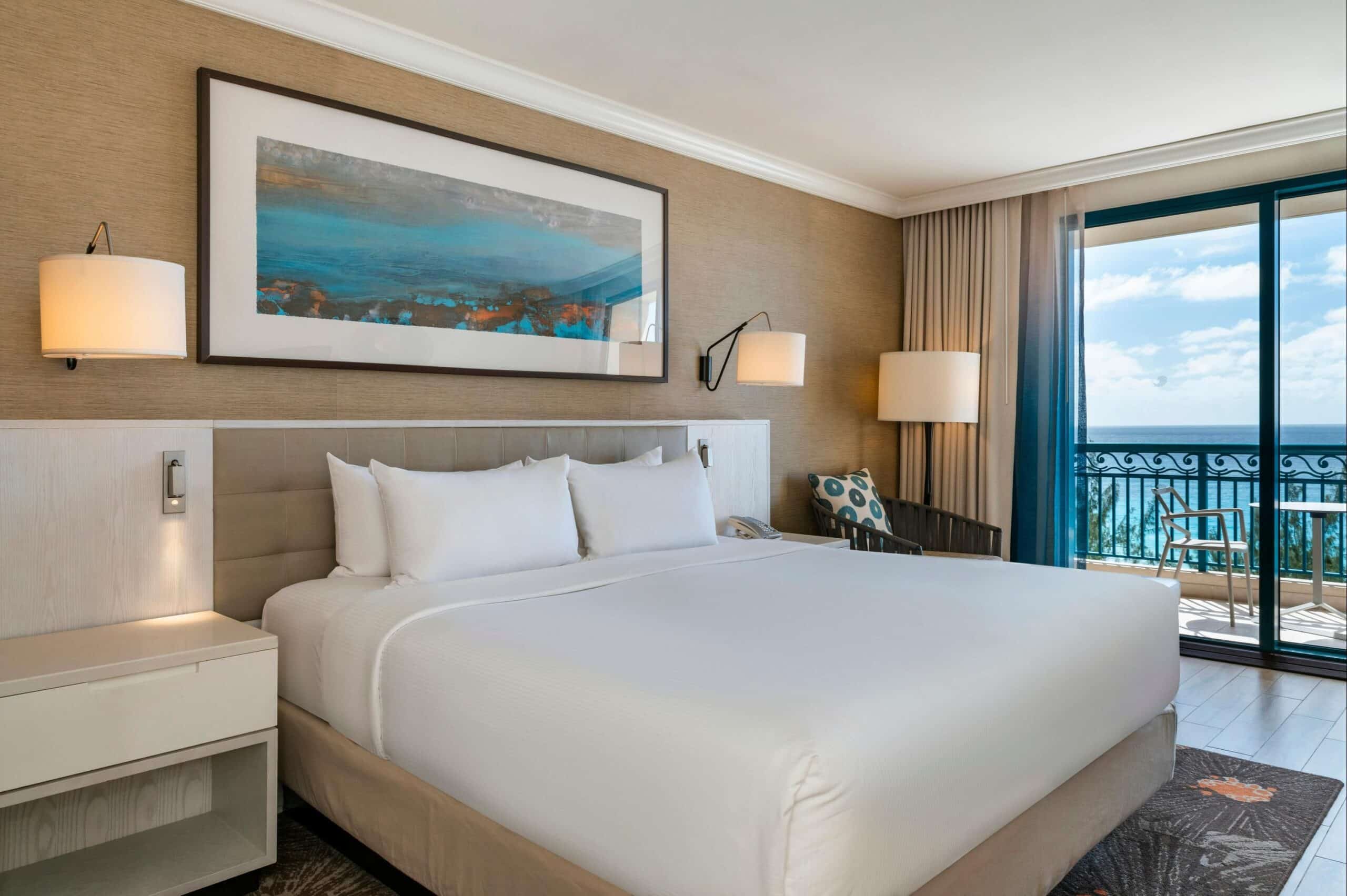 http://Chambre%20d’hôtel%20moderne%20avec%20grand%20lit,%20balcon%20privé%20et%20vue%20sur%20l’océan%20dans%20les%20Caraïbes.