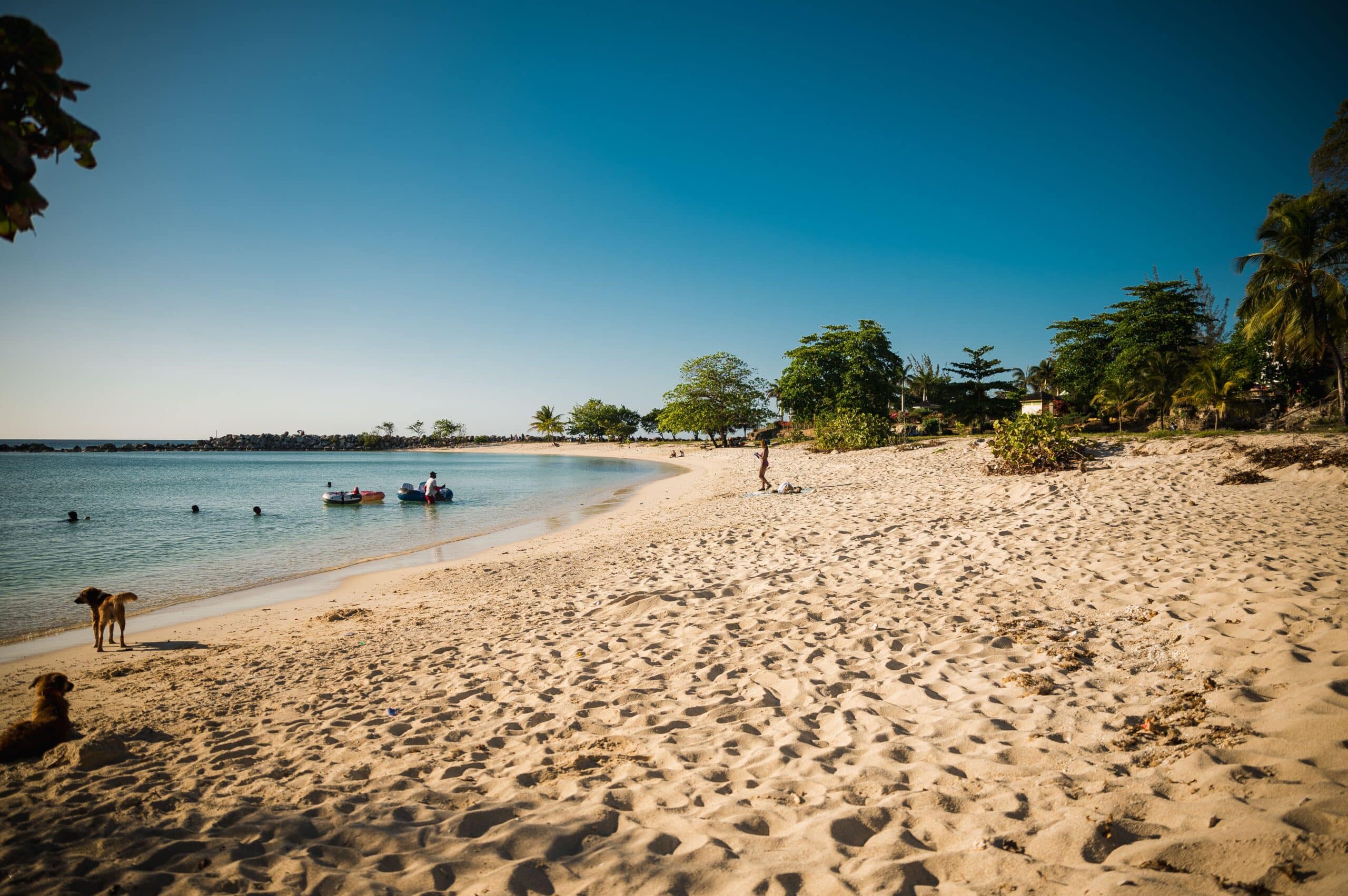 http://Plage%20de%20sable%20fin%20avec%20eaux%20calmes%20et%20quelques%20vacanciers%20profitant%20du%20littoral%20jamaïcain.