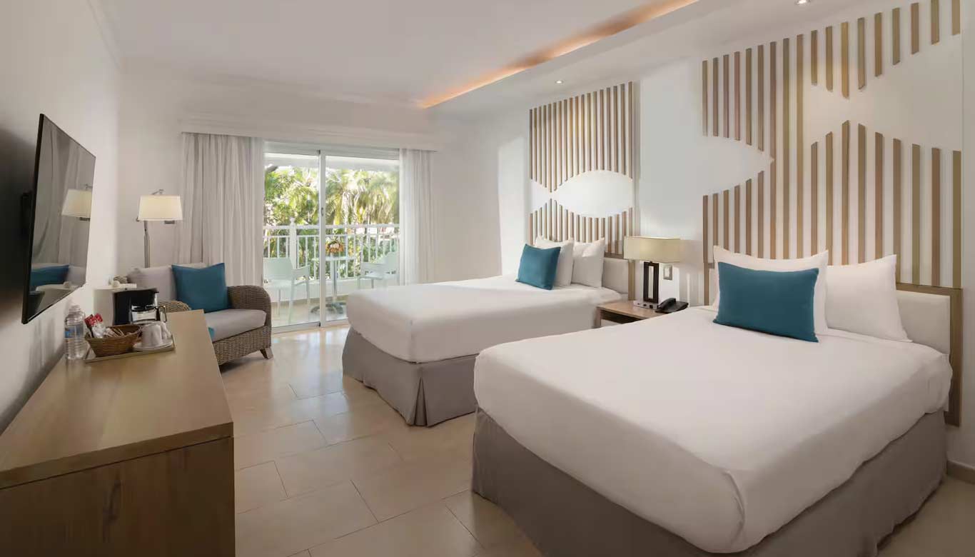 http://Chambre%20d'hôtel%20moderne%20avec%20deux%20grands%20lits,%20décoration%20contemporaine%20et%20balcon%20donnant%20sur%20les%20jardins.