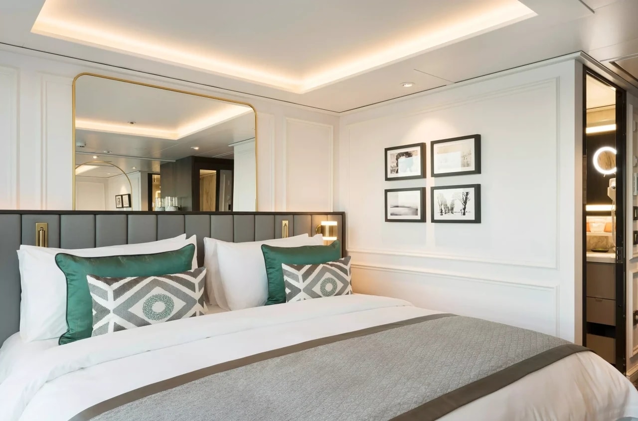 Cabine de bateau de croisière fluviale avec lit double, décoration élégante et salle de bains attenante.