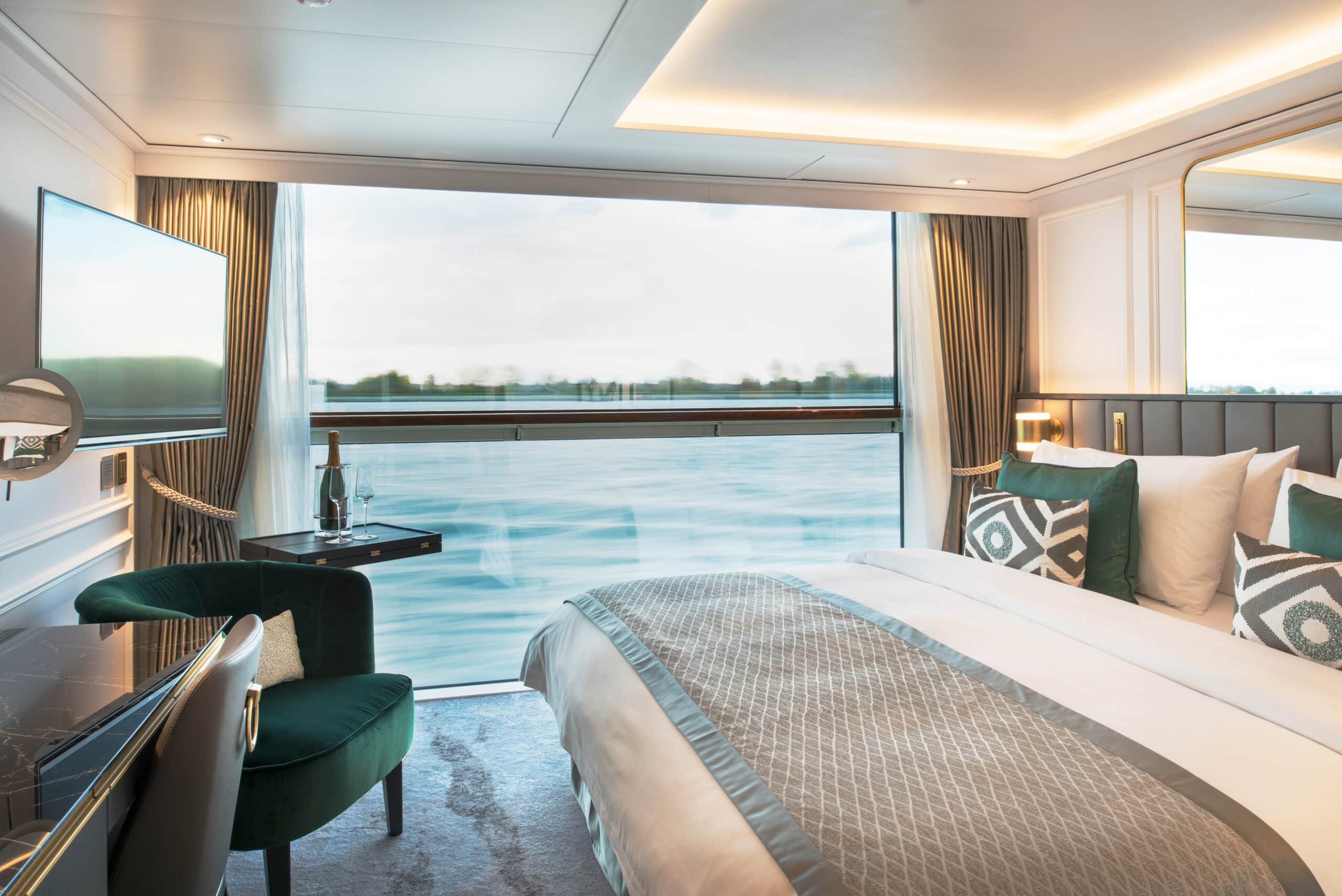 Cabine élégante d’un bateau de croisière avec lit double et grande baie vitrée donnant sur le Rhône.