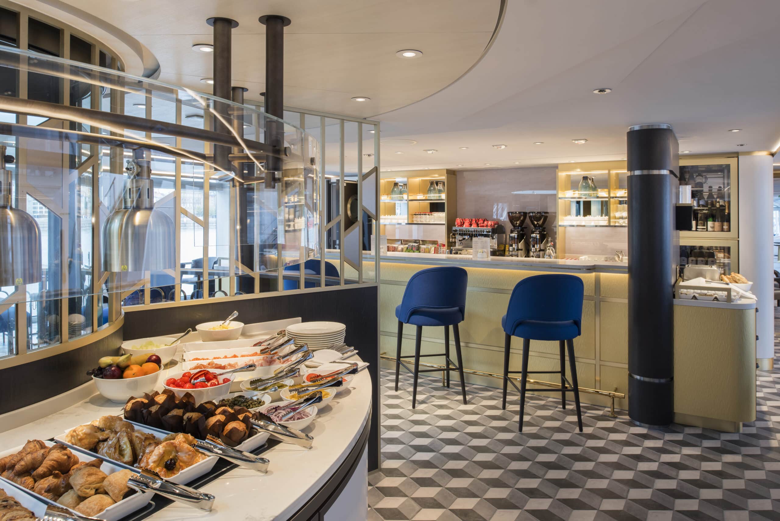 Buffet de petit-déjeuner avec viennoiseries, fruits et plats variés dans le restaurant d’un bateau de croisière.
