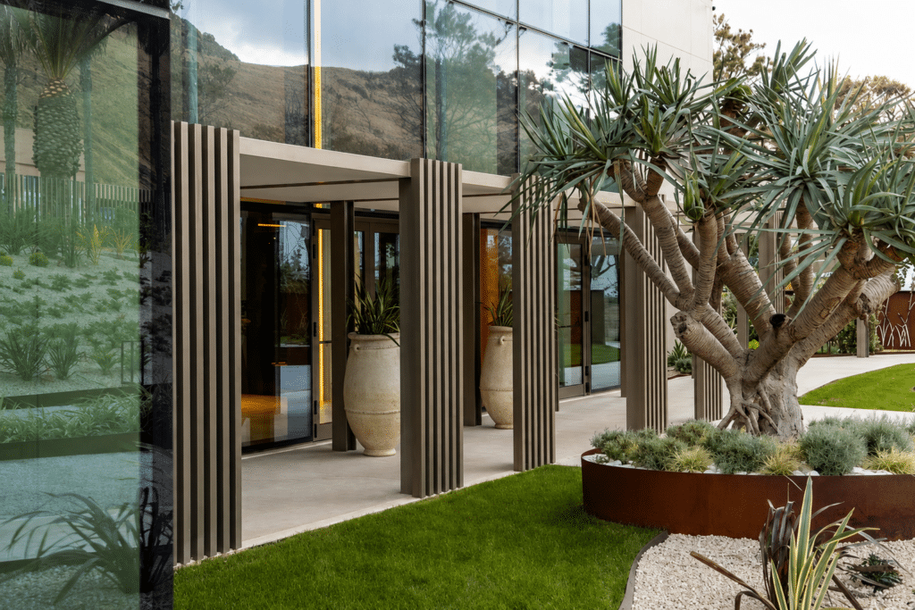 Entrée contemporaine d’un hôtel entourée d’un jardin paysager avec végétation méditerranéenne.