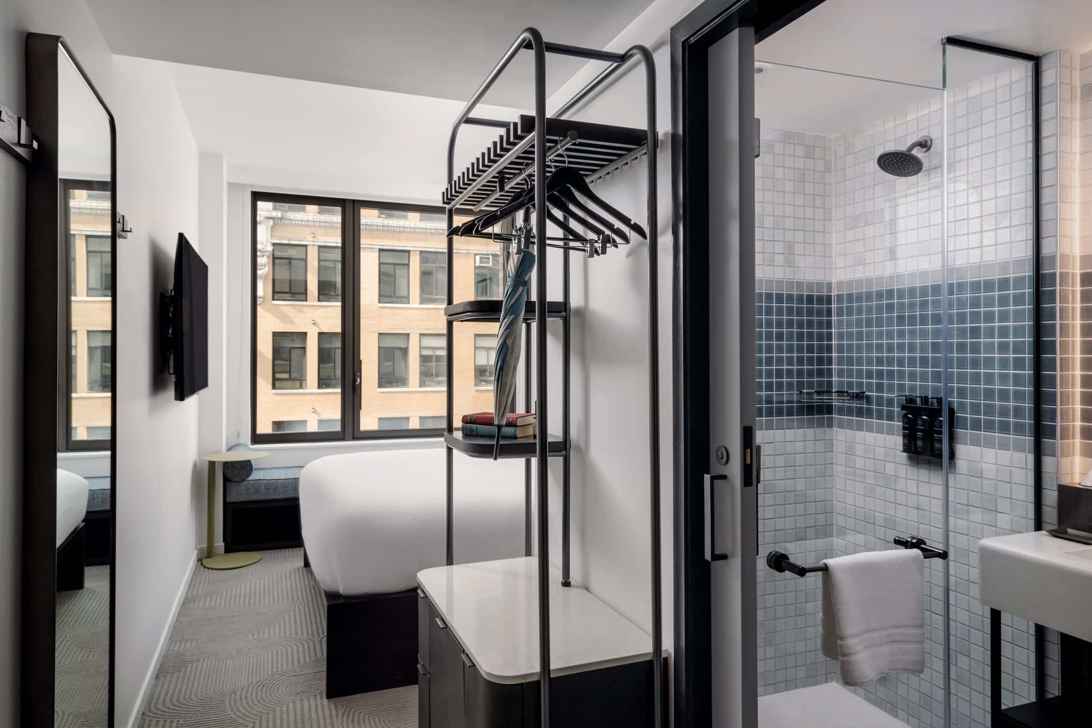 http://Chambre%20d’hôtel%20moderne%20à%20New%20York%20avec%20lit%20double%20et%20salle%20de%20bains%20ouverte%20équipée%20d’une%20douche.