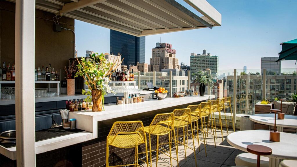 Rooftop avec bar, terrasse aménagée et vue sur les immeubles de Manhattan à New York.