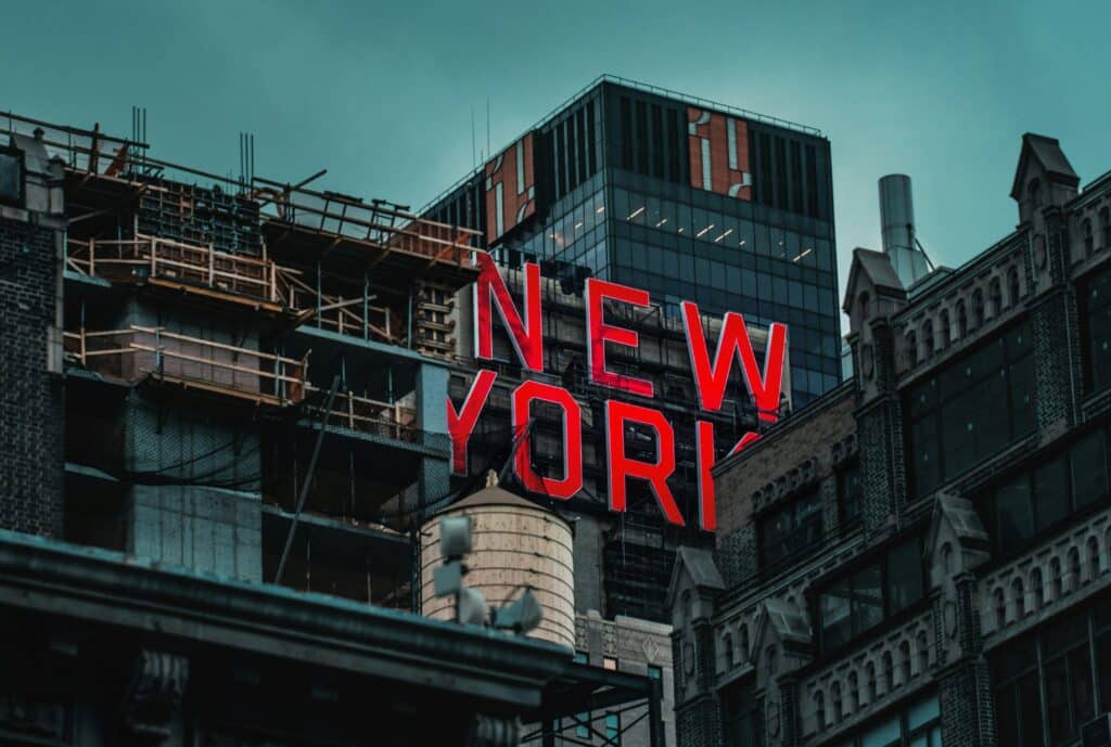 Enseigne New York en lettres rouges entourée d’immeubles urbains à Manhattan.