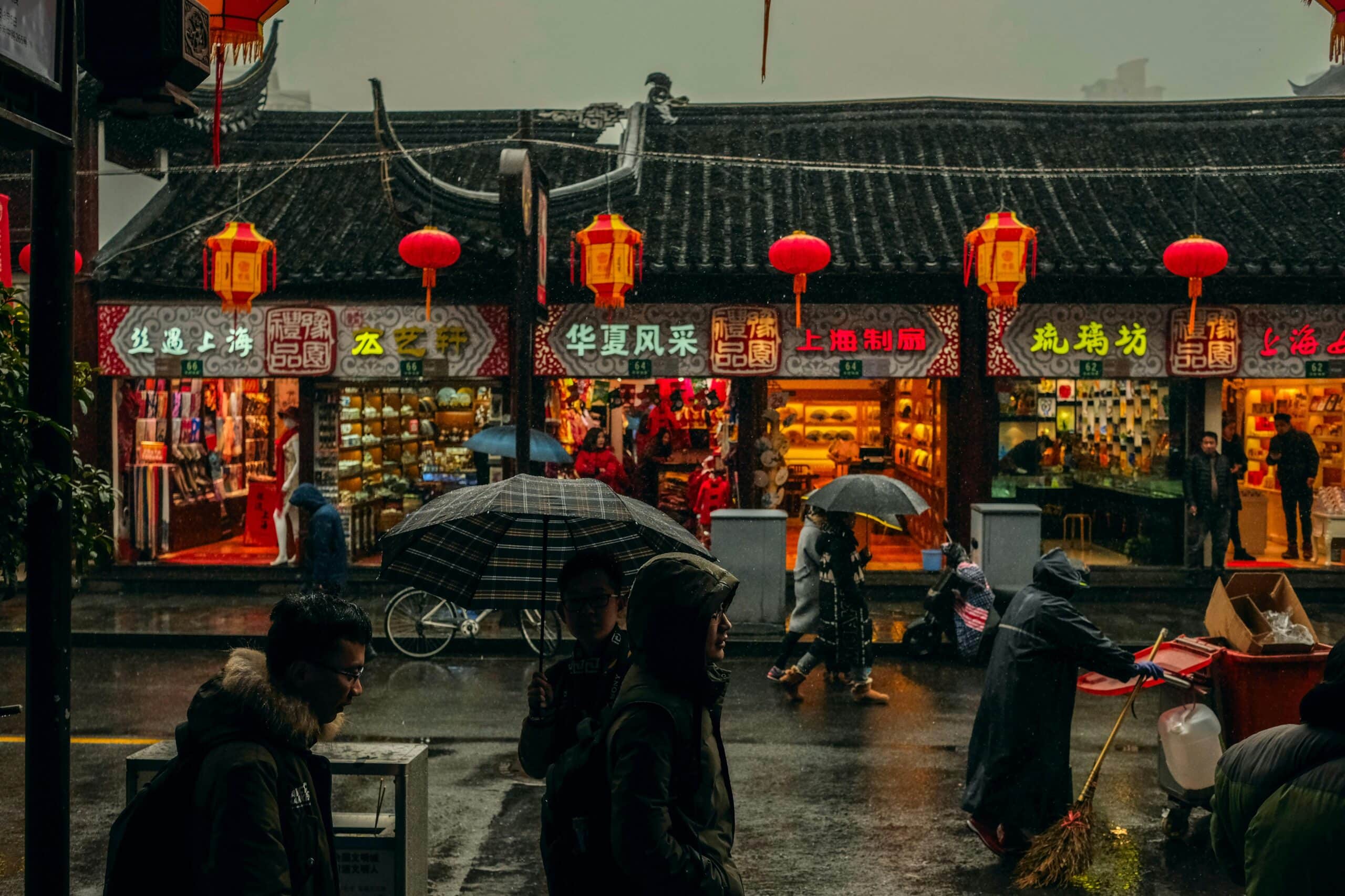 http://Rue%20commerçante%20traditionnelle%20en%20Chine%20sous%20la%20pluie,%20décorée%20de%20lanternes%20rouges%20et%20bordée%20de%20boutiques.