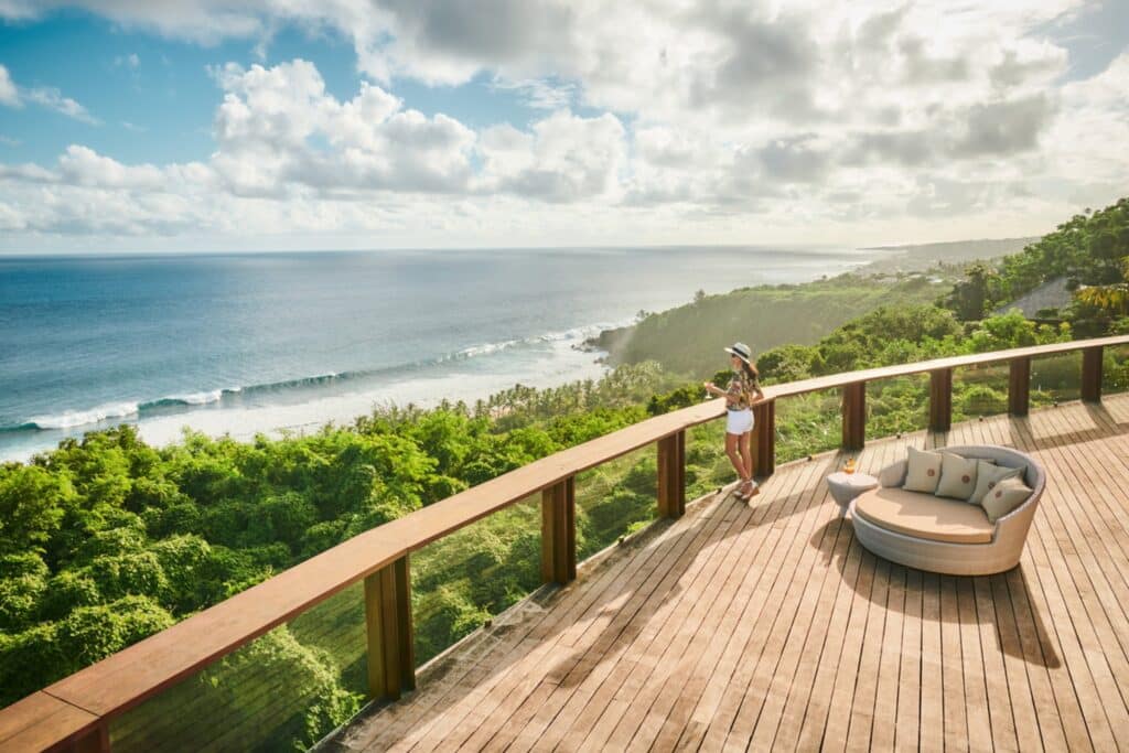 Terrasse panoramique en bois dominant une côte tropicale verdoyante et l’océan.