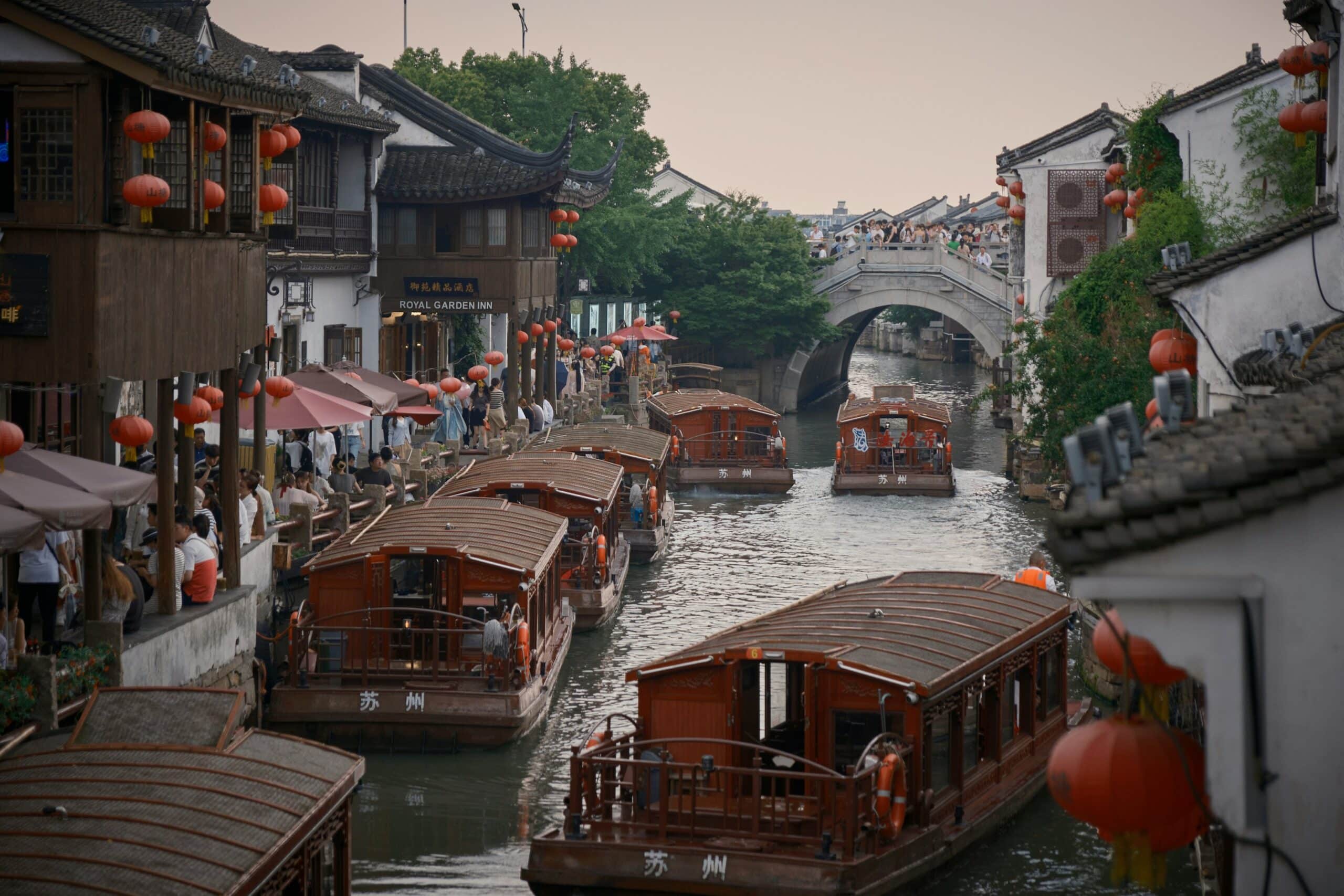 http://Bateaux%20naviguant%20sur%20un%20canal%20de%20Suzhou%20bordé%20de%20maisons%20traditionnelles%20chinoises%20et%20de%20lanternes%20rouges.