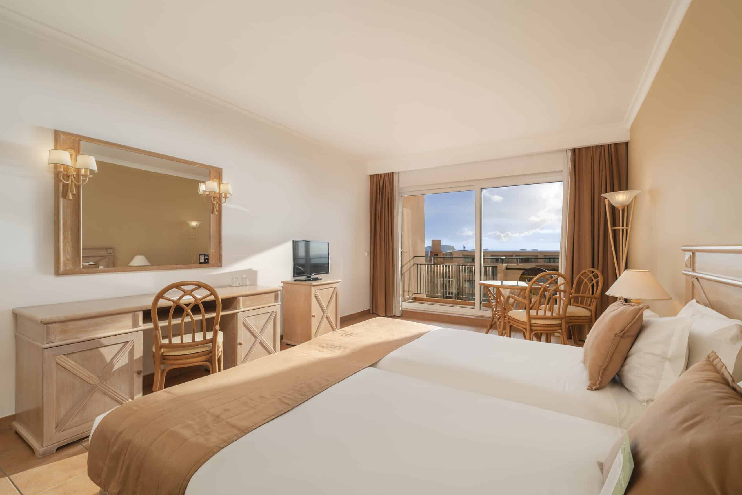 http://Chambre%20d’hôtel%20lumineuse%20à%20Porto%20Santo%20avec%20deux%20lits,%20mobilier%20en%20bois%20clair%20et%20balcon%20avec%20vue%20extérieure.