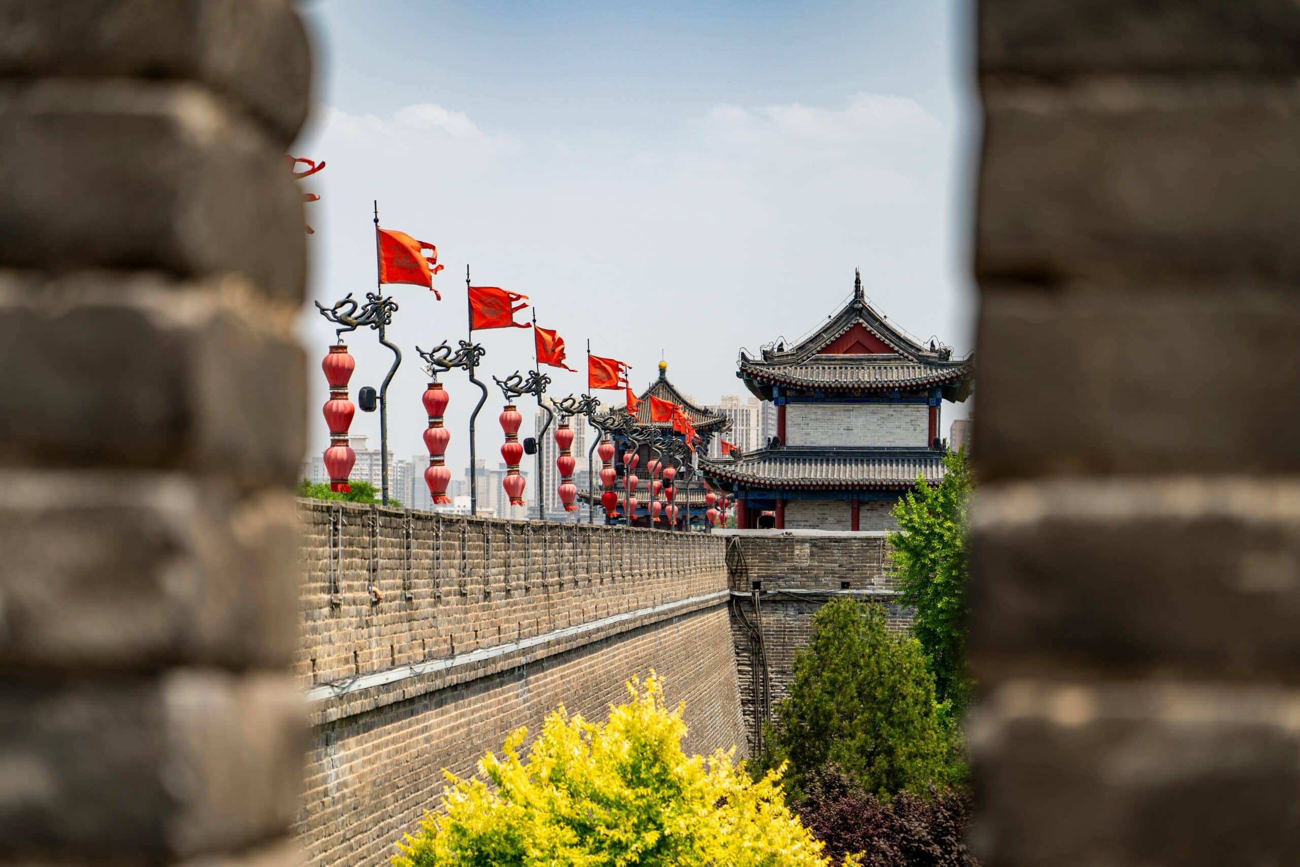 http://Remparts%20de%20Xi’an%20en%20Chine%20avec%20tour%20traditionnelle,%20lanternes%20rouges%20et%20drapeaux%20le%20long%20des%20fortifications.