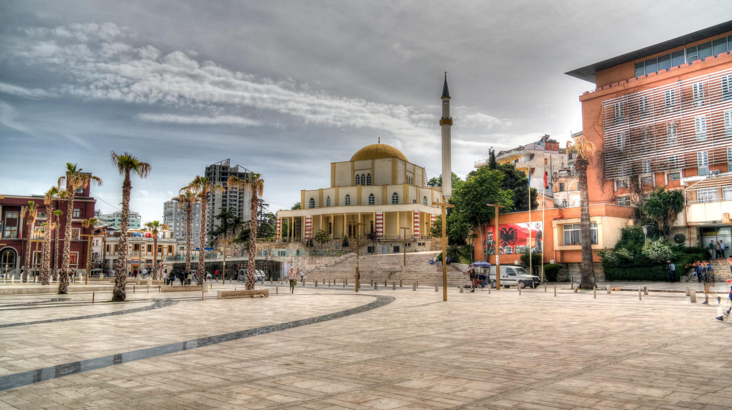 Mosquée avec dôme et minaret dominant une grande place urbaine en Albanie.