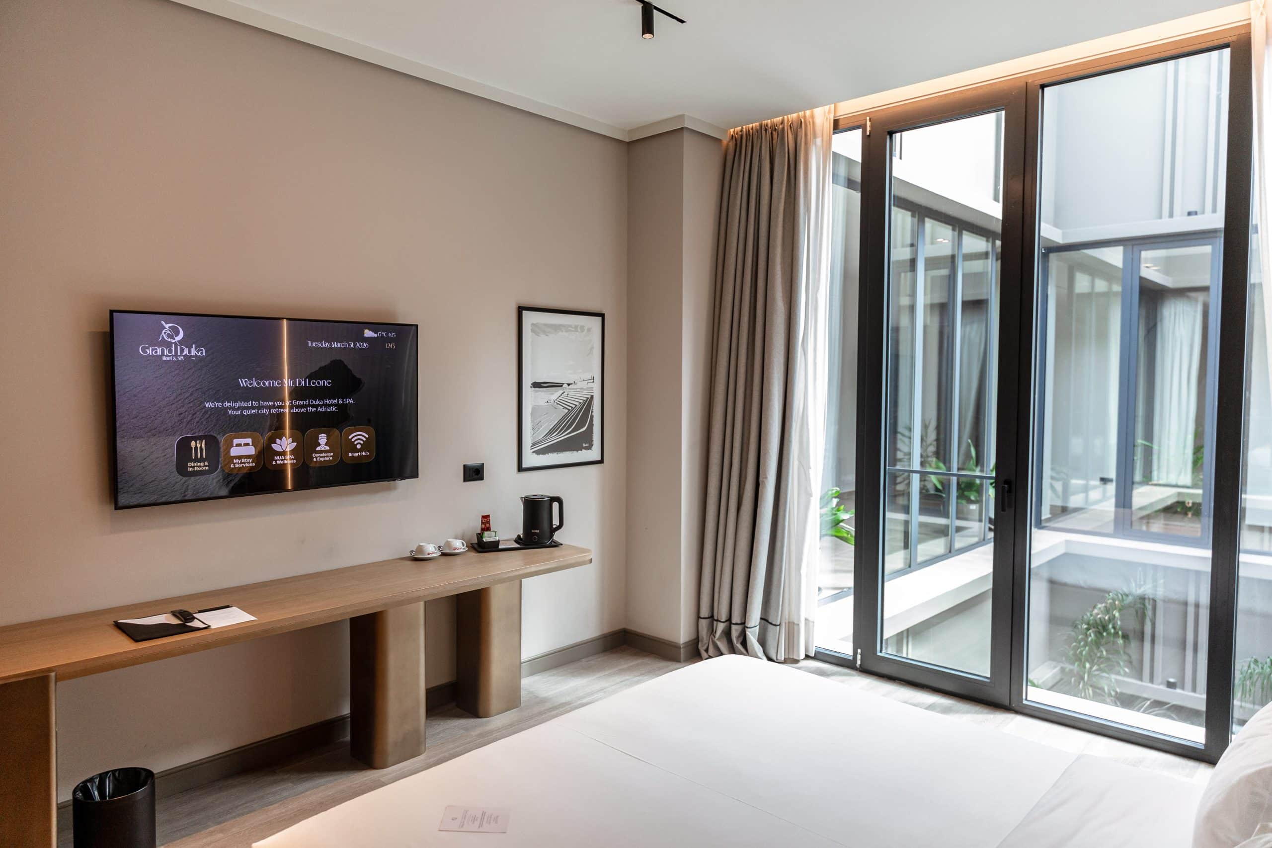 Chambre moderne du Grand Duka Hotel & SPA avec télévision et grandes baies vitrées.