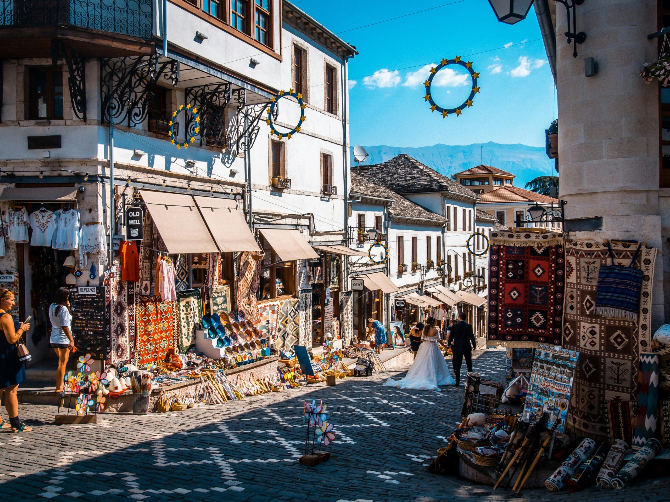Rue pavée d’une ville historique d’Albanie bordée de boutiques de tapis et d’artisanat traditionnel.