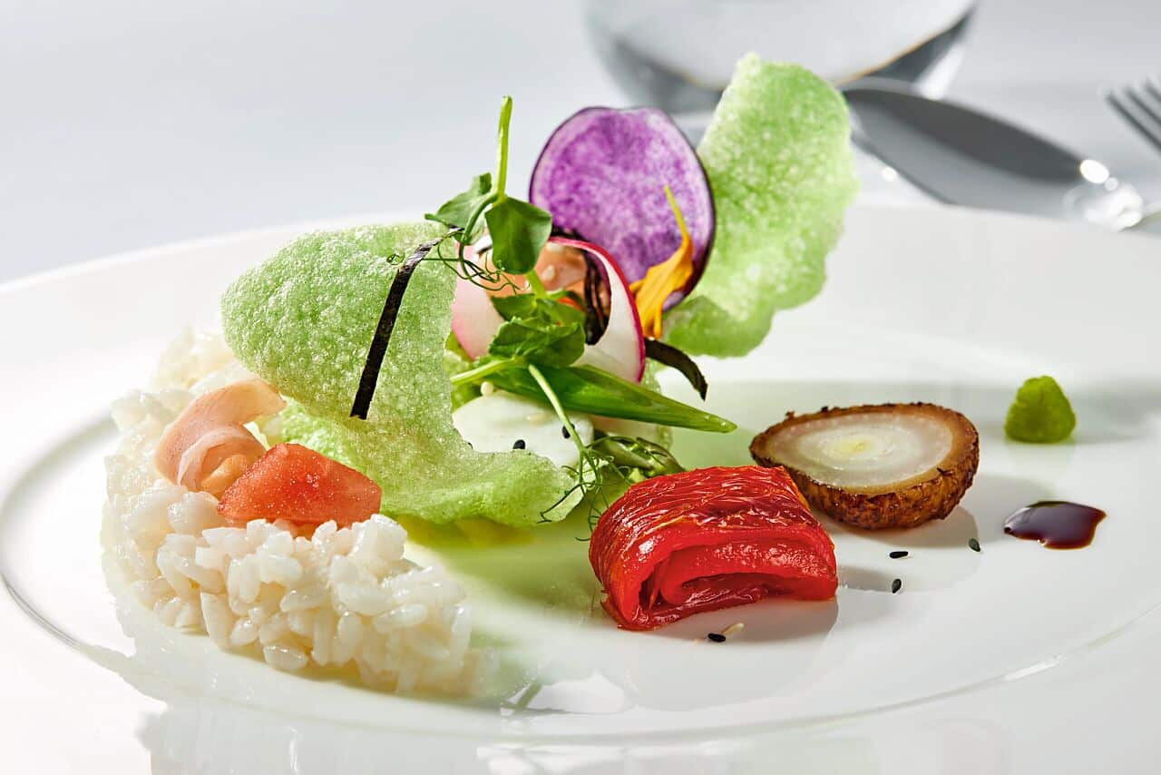 Assiette gastronomique composée de légumes, riz et garnitures raffinées servie à bord d’un bateau de croisière.