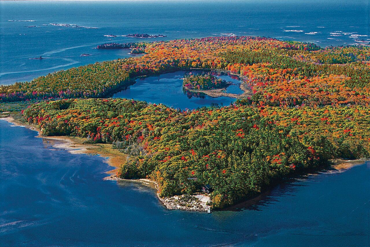 Vue aérienne d’îles boisées aux couleurs de l’automne entourées d’eaux bleues au Canada.