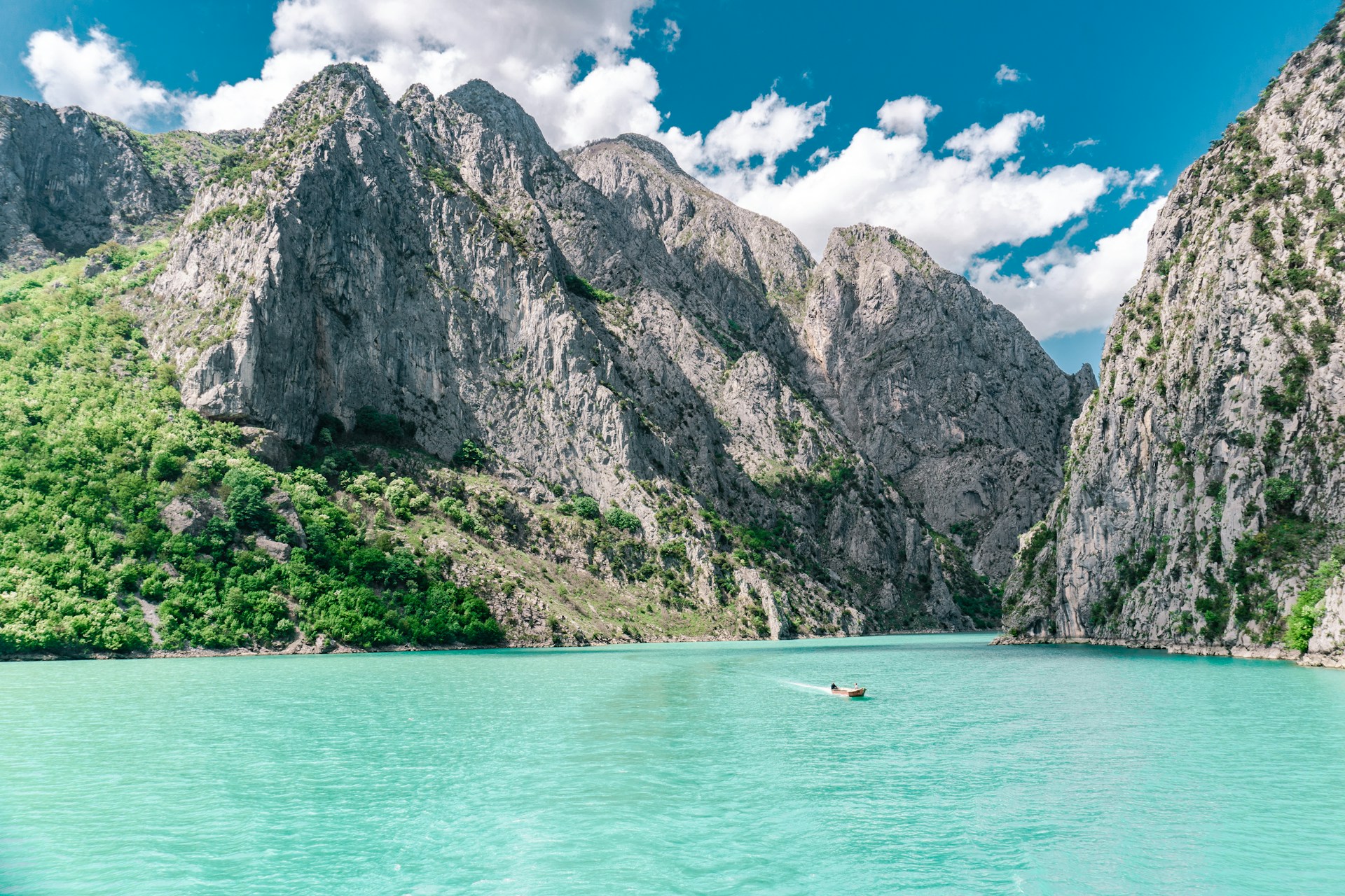 Le lac Koman en Albanie, entouré de falaises verdoyantes et de fjords sauvages aux reflets émeraude dans le nord du pays.