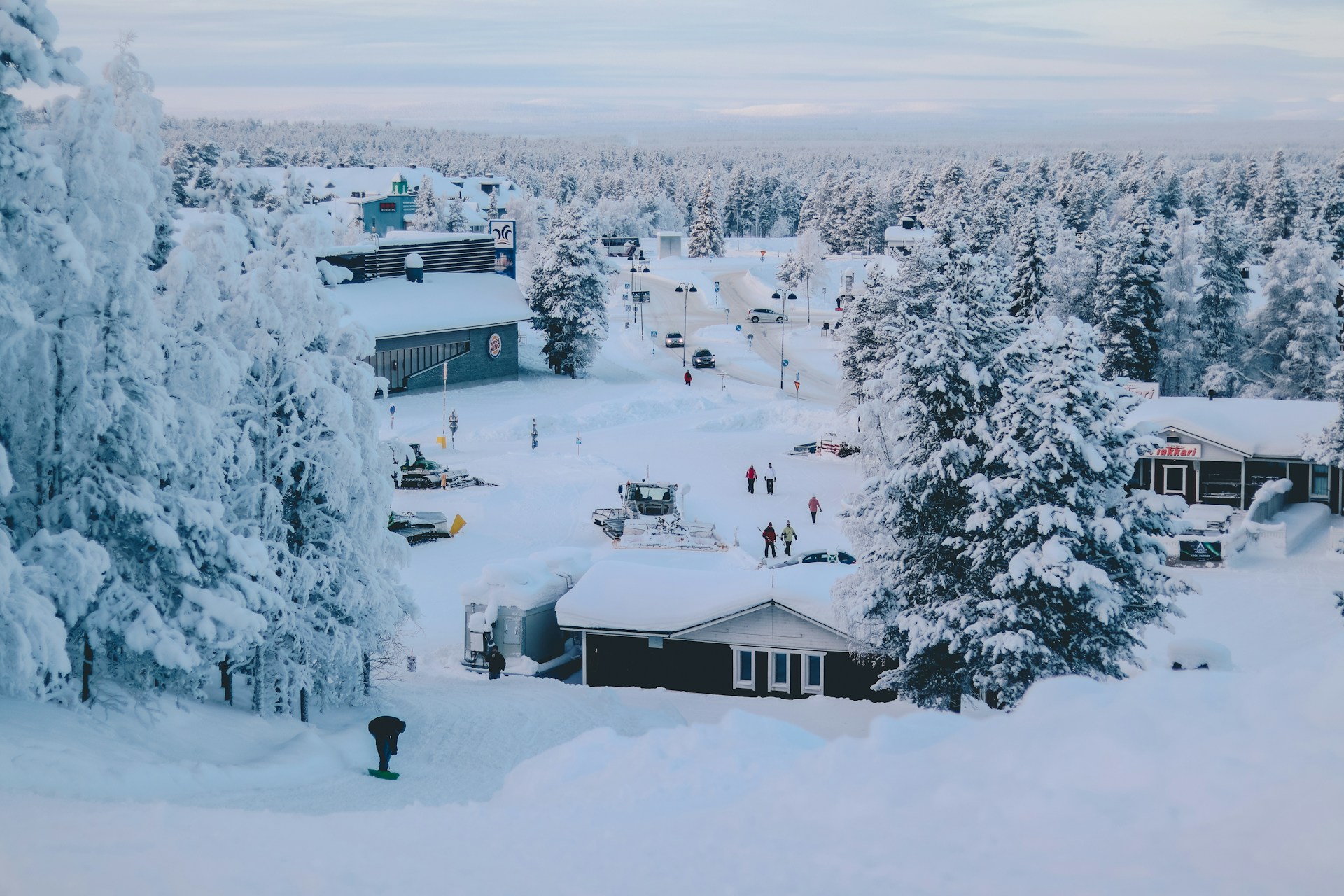 Village traditionnel de Laponie enneigé avec ses cabanes en bois et ses forêts de sapins recouverts de neige.