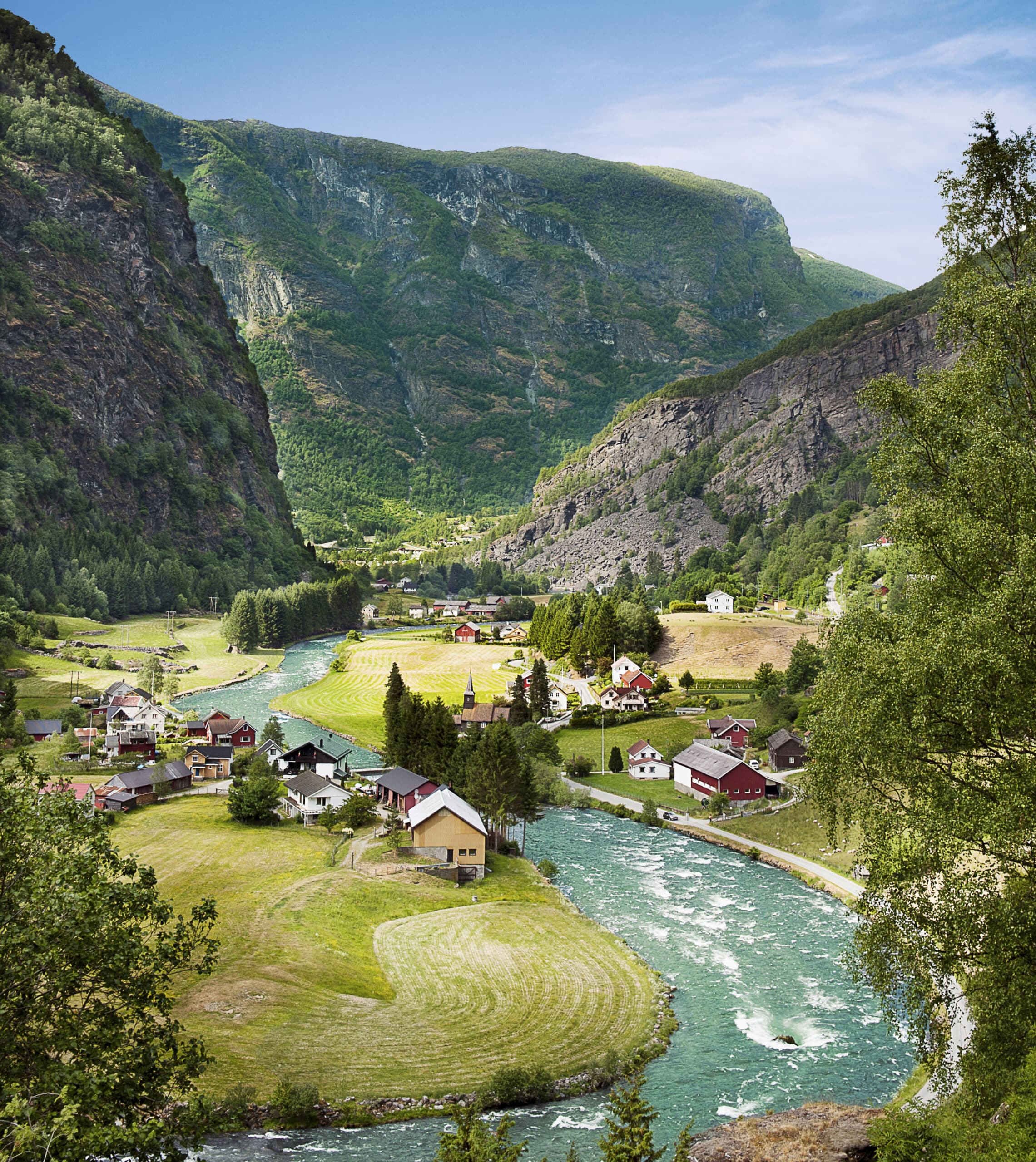 Village norvégien traversé par une rivière turquoise au cœur d’une vallée montagneuse