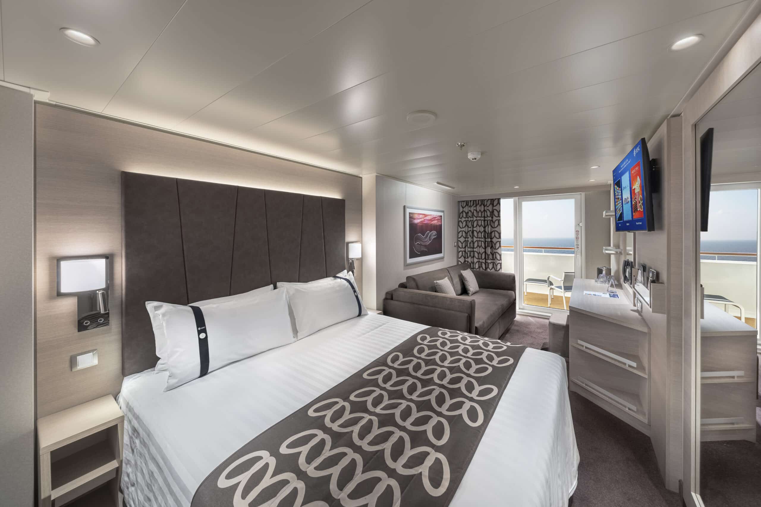 Cabine de navire de croisière avec lit double, espace salon et balcon donnant sur la mer