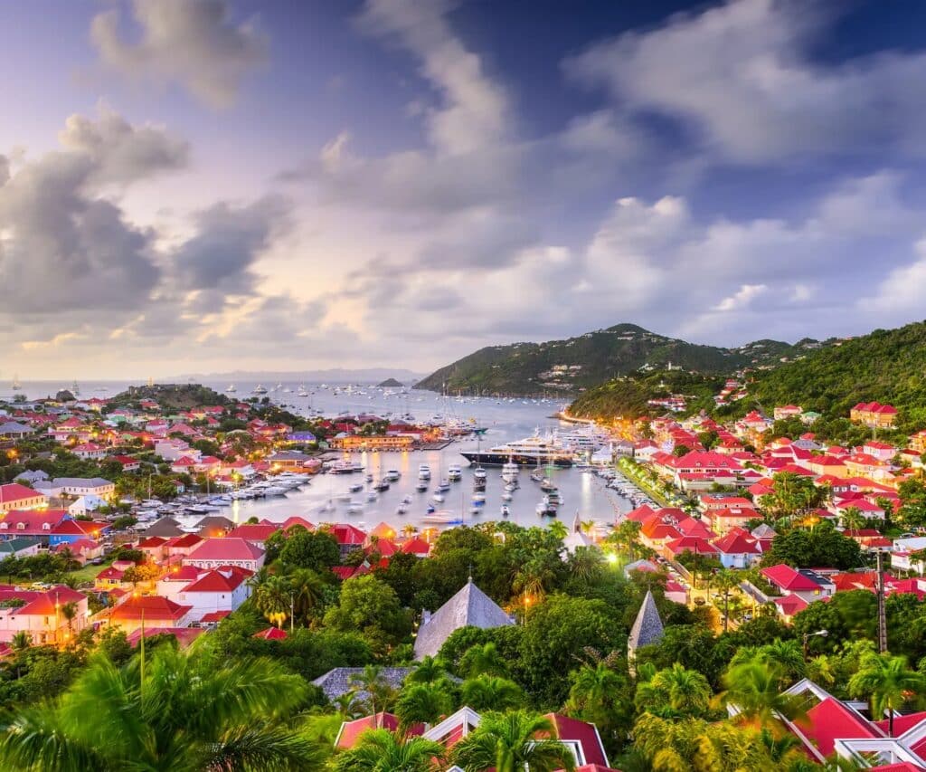 Vue panoramique du port de Gustavia à Saint-Barthélemy au crépuscule, avec ses maisons aux toits rouges, ses yachts et ses collines verdoyantes.